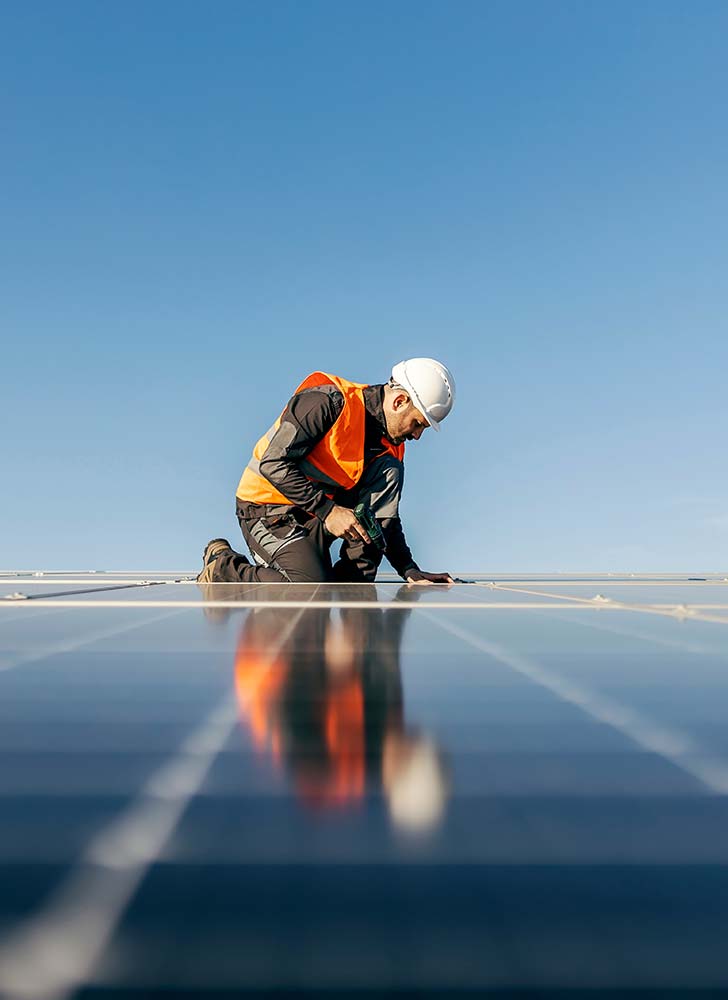 A man on a roof installing solar panels, performing a solar panel installation