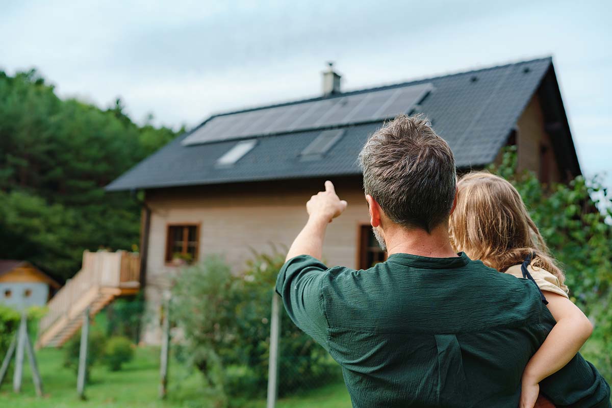 Man showing his daughter the new solar panel installation on their home.