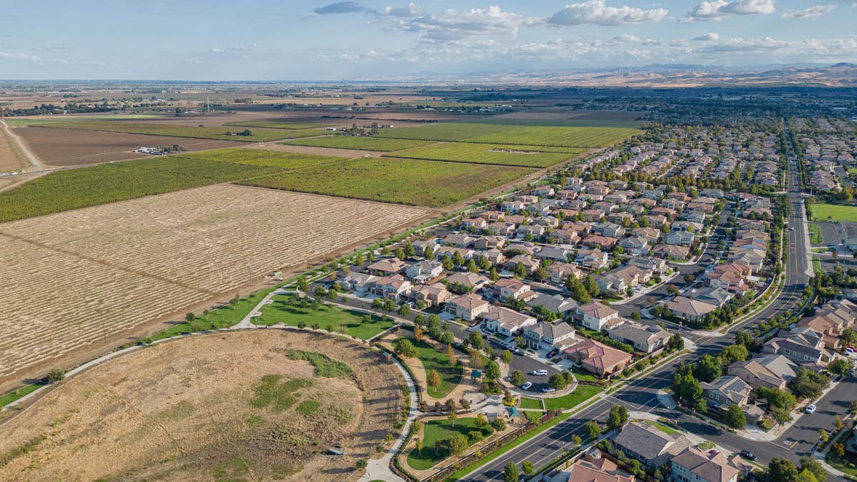 Aerial view showing farmland bordering suburban housing developments, illustrating the loss of agricultural land to permanent development and why farmland protection matters in New England.