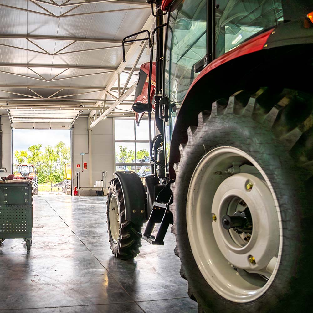 Farm equipment inside a Greenfield agricultural barn with natural light coming through the open bay doors.