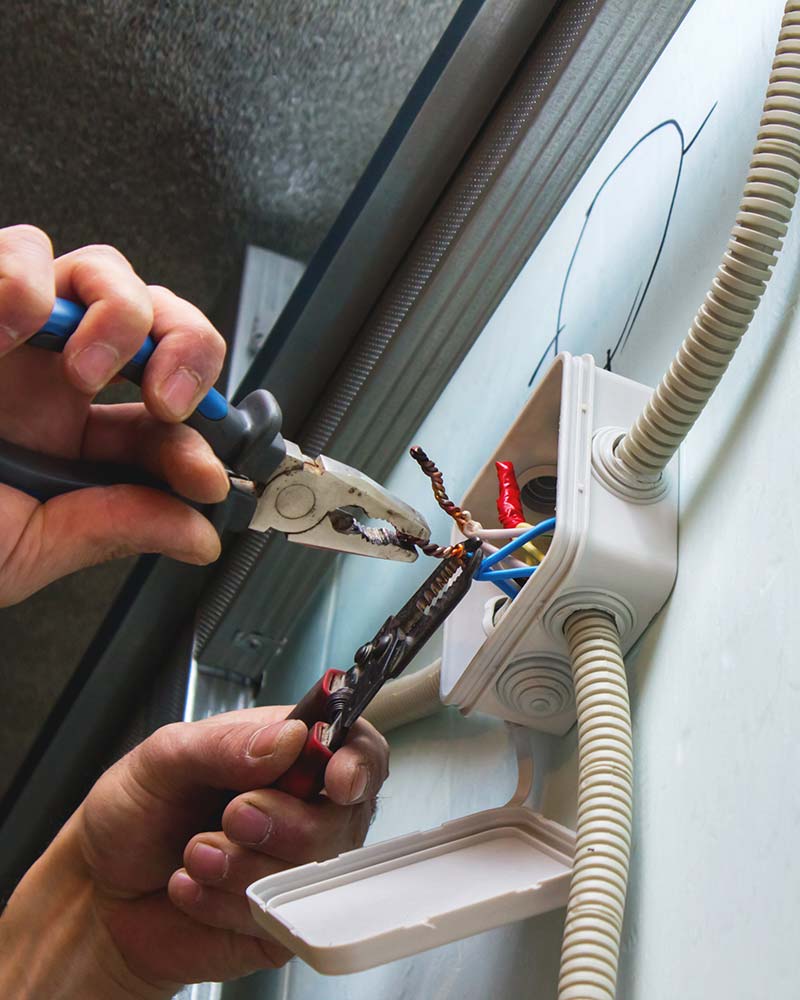Hands twisting electrical wires in a junction box, illustrating standard wiring safety procedures used in Greenfield homes.