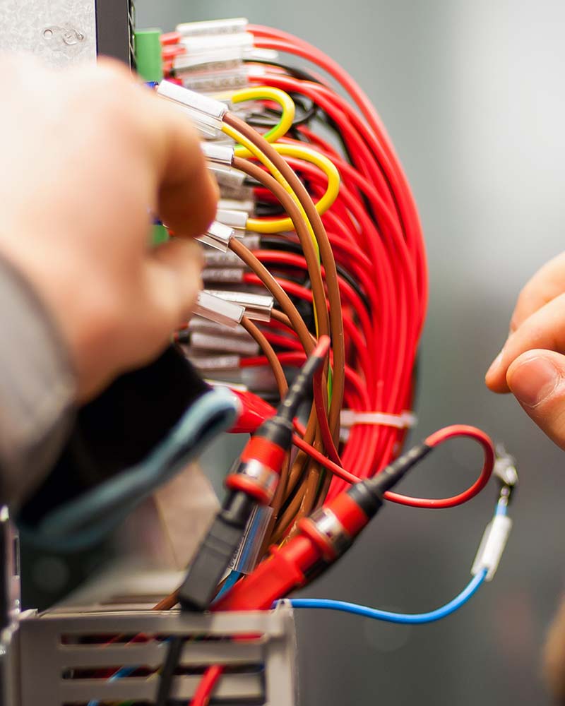 Technician organizing complex wiring in an electrical panel, an example of organized system management in Greenfield.