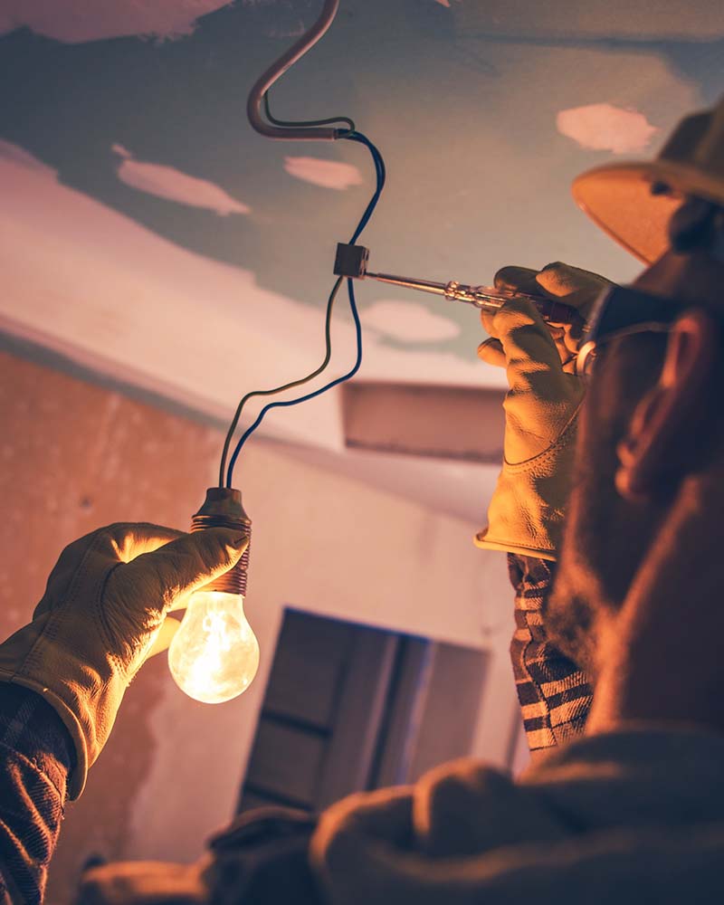 Electrician testing a light socket voltage, part of the electrical troubleshooting services available in Greenfield.