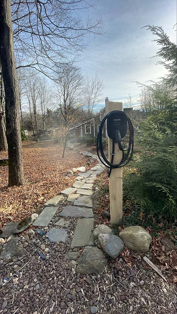 Post-mounted Emporia EV charger near a stone path, a landscape-friendly option for Greenfield properties.