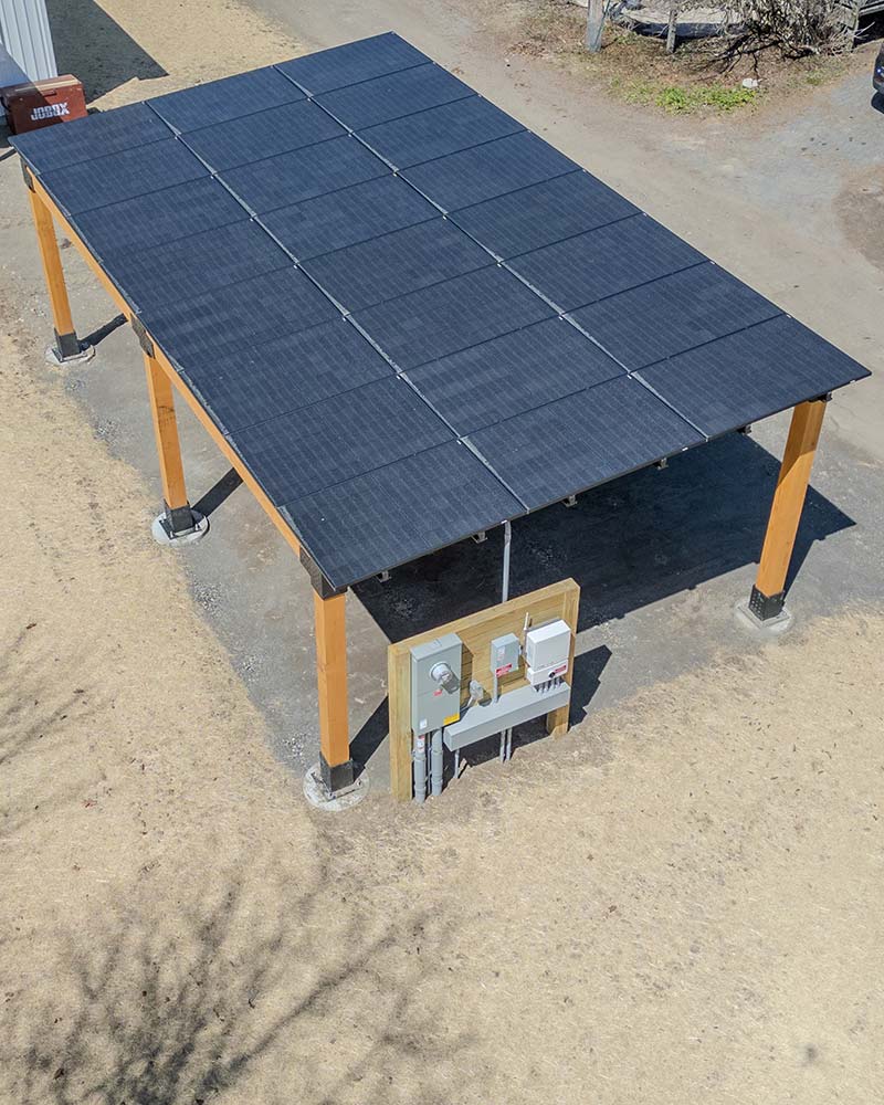 Timber-frame solar carport with black panels, an example of solar structures available for Greenfield, MA properties.
