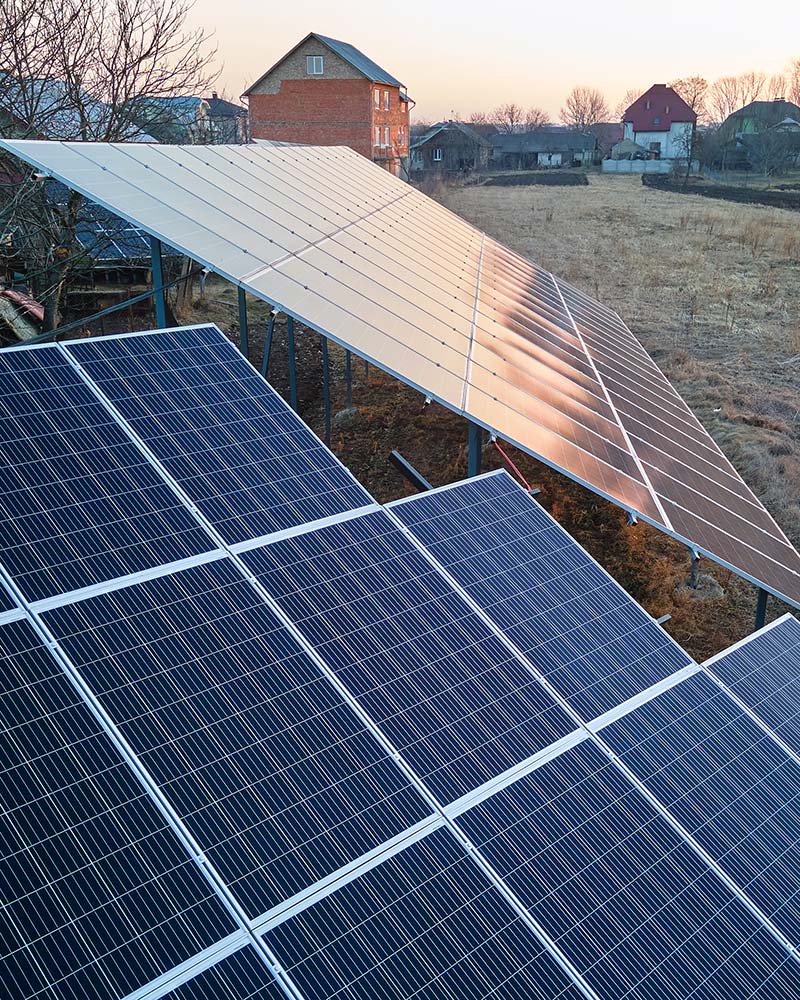 Angled view of solar panels at sunset, illustrating ground mount placement for Greenfield homes.