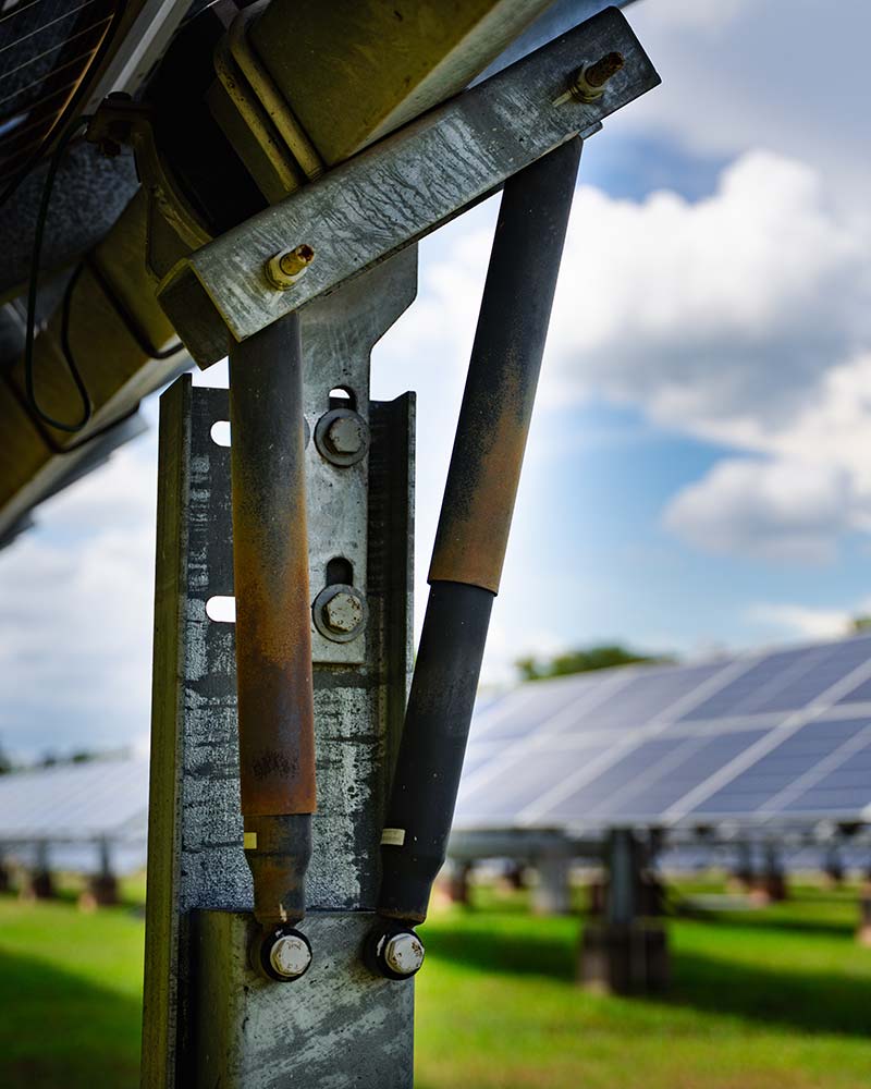 Close-up of solar racking mechanism with hydraulic support, an example of engineering used in Greenfield solar projects.