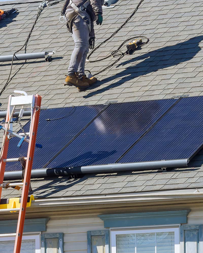 Technician preparing a roof for solar panel mounting, similar to installations Current Energy provides in Greenfield, MA.