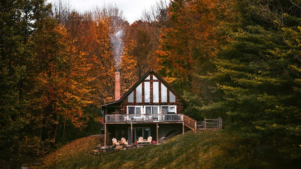 Solar and wood heat for homes in Southern Vermont, hillside cabin with chimney smoke in fall