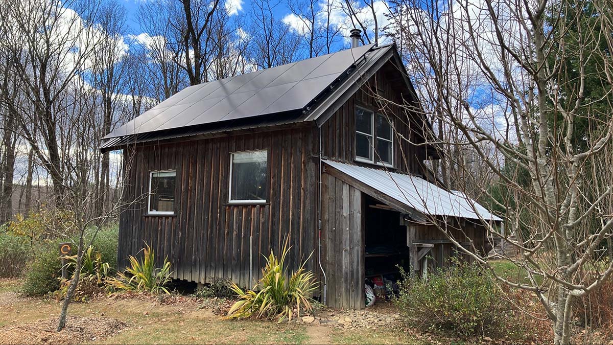 Shelburne residential solar installation on roof-mounted cabin system in rural wooded setting