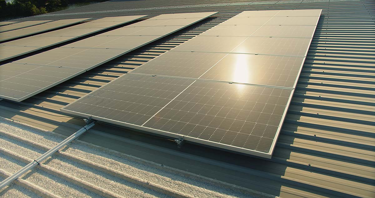 Commercial solar installation in Greenfield MA on metal roof with sun reflecting across panels