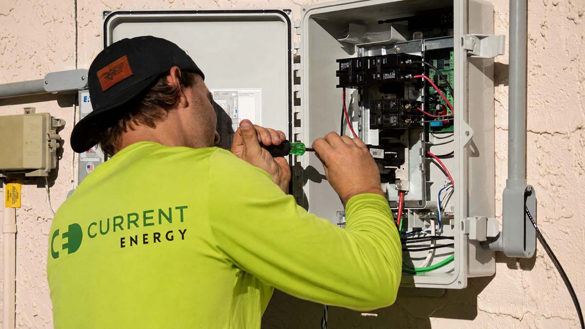 Current Energy technician working on an electrical panel, showing the electrical review often needed before adding solar to an older home.