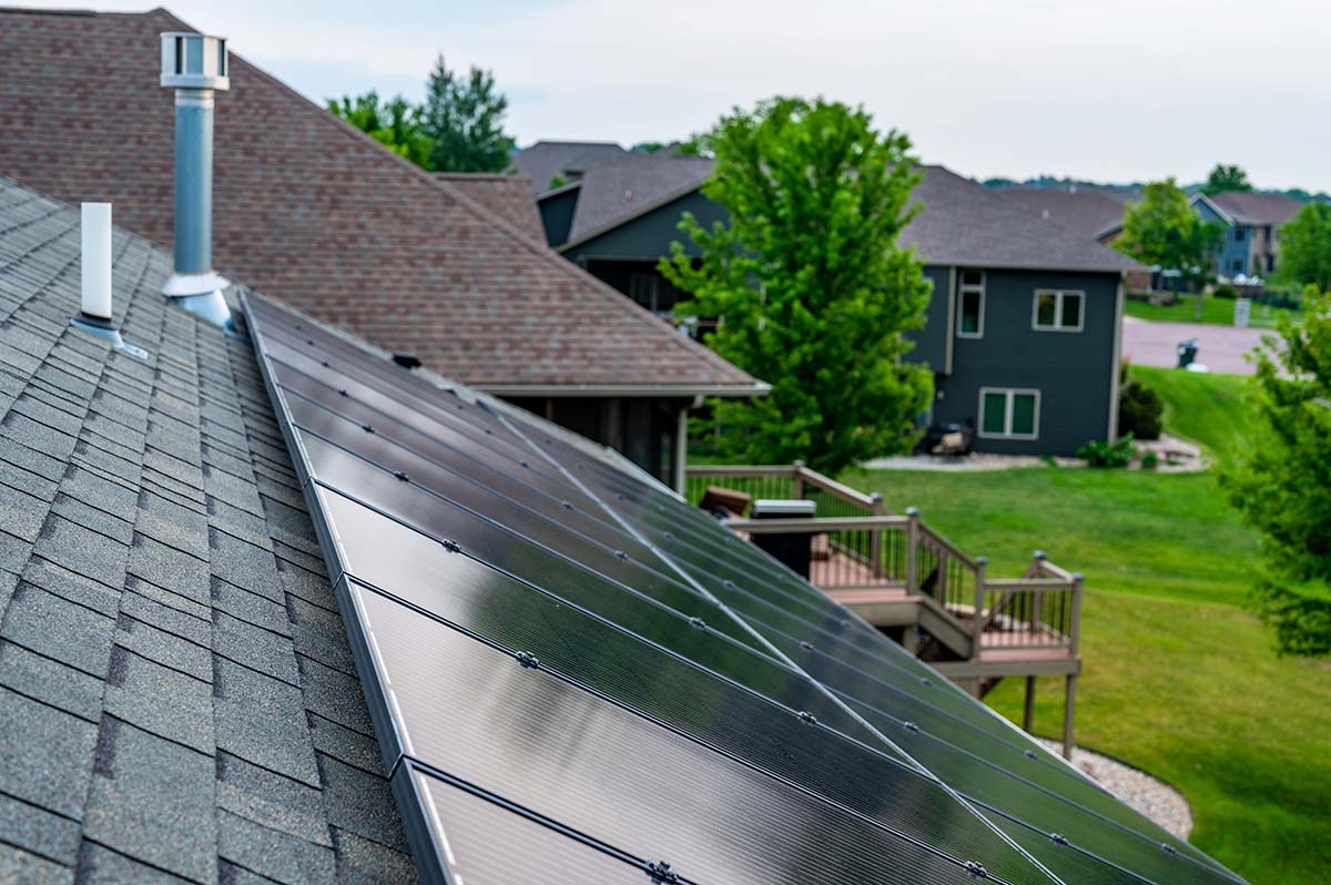 Solar panel installation in Western Massachusetts on residential roof with neighborhood landscape in background